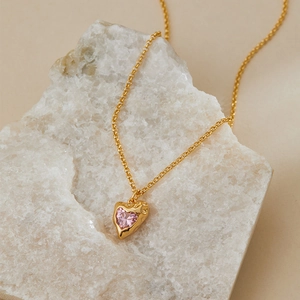 Detail of pink heart gemstone and textured lava gold pendant on a delicate chain