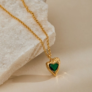 Close-up of heart-shaped green zircon necklace with vintage gold hammered texture