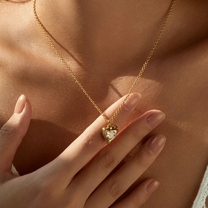 Vintage gold heart pendant necklace with zircon stone on model's neckline
