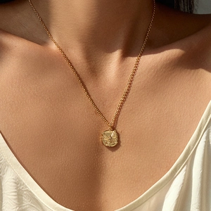 Close-up of 18K gold plated butterfly medallion necklace worn on neck with sunlight