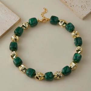 Dettaglio della collana con cubi di malachite verde e perle dorate in metallo irregolare