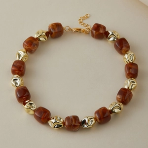Dettaglio di perle in acrilico ambra e perle dorate irregolari sulla collana