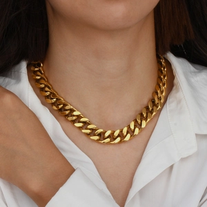 Close-up of a thick gold-plated Cuban link chain necklace worn on a person's neck