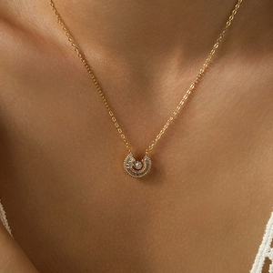 Macro shot of 18K gold plated horseshoe pendant with cubic zirconia on female collarbone