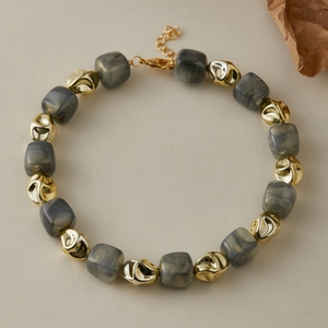 Dettaglio delle perle in acrilico marmorizzato grigio e delle perle metalliche dorate