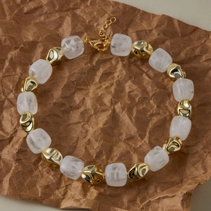 Dettaglio di perle quadrate bianche opache e perline di metallo dorato su una collana