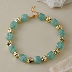 Dettaglio della collana con perle di resina verde marmorizzata e sfere dorate irregolari