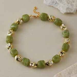 Dettaglio della collana di perline con cubi di resina verde e accenti metallici dorati