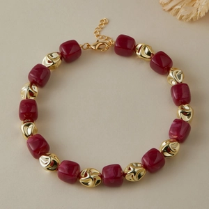 Dettaglio delle perle in acrilico bordeaux e perle di metallo dorato sulla collana fatta a mano