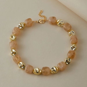 Dettaglio di cubi in resina ambra e perle dorate irregolari sulla collana elegante