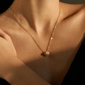 Close-up of 18K gold plated necklace featuring a round pearl and crystal halo pendant