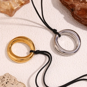 Détail des pendentifs anneaux en or 18 carats et argent sur cordons noirs tressés