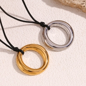 Détail de pendentifs circulaires or et argent sur cordons noirs avec finition polie
