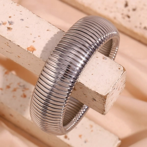 Detailed view of silver Tubogas elastic metal bracelet on a textured stone display