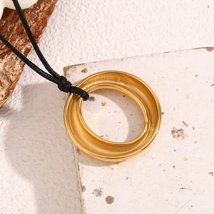 Détail du pendentif circulaire entrelacé plaqué or 18K sur un cordon noir tressé