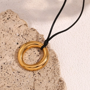 Gros plan d'un pendentif anneau plaqué or 18 carats poli sur un cordon noir minimaliste