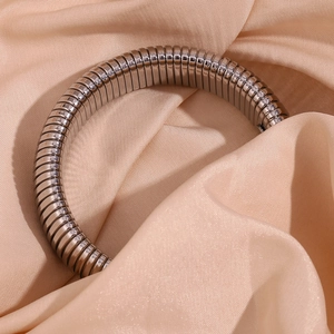 Detailed view of a silver-toned flexible snake chain bracelet on satin fabric