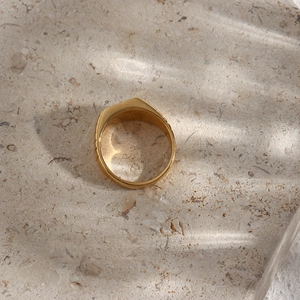 Close-up of a wide polished gold ring on stone background with creative lighting