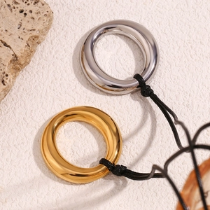Vue macro de pendentifs circulaires polis en or et argent avec cordons tressés noirs