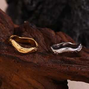 Détail de bagues plaquées or 18 carats avec texture martelée ondulée sur bois sombre