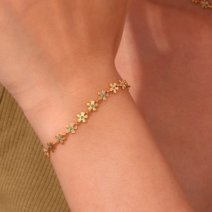 Detailed shot of gold floral chain bracelet with turquoise beads on a model's wrist