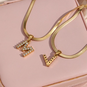 Λεπτομέρεια από επιχρυσωμένες αλυσίδες 18K με μενταγιόν γράμματα M και V με ζιργκόν