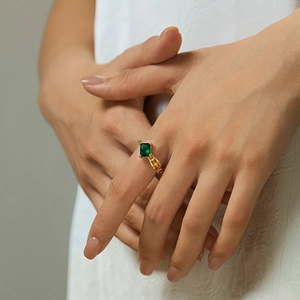 Detailed shot of an 18K gold ring with a rectangular green zircon stone on a model hand