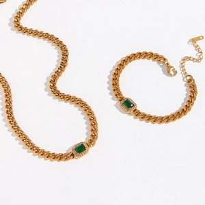 Detail of gold Cuban chain set with rectangle green gemstone and 18K gold hallmark