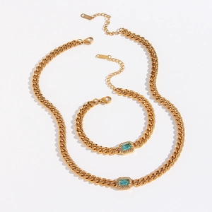 Detail of 18K gold Cuban link jewelry set with emerald-cut blue zircon and stone halo