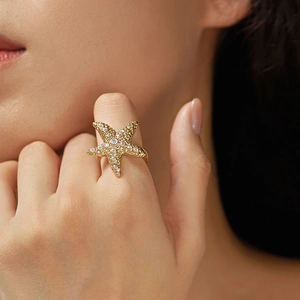 Detail of bohemian gold-plated starfish ring with cubic zirconia worn by model