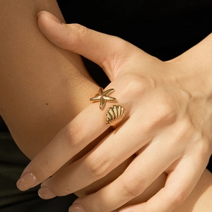 Bohemian 18K gold starfish and seashell open ring shown on a finger for beach style
