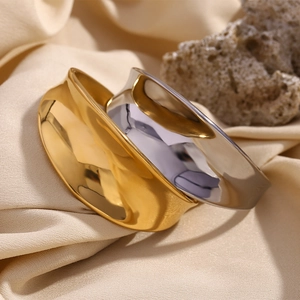 Macro shot of minimalist 18K gold and silver layered wavy open bangles with mirror finish