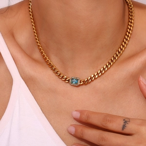 Detail of gold Cuban chain with rectangular blue zircon pendant on female model