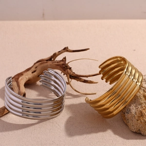 Detail of wide multi-layer ribbed cuff bracelets in 18K gold and silver polished finish