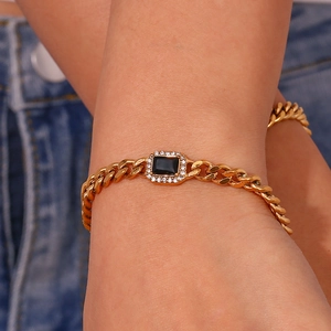 Detail of golden Cuban link bracelet with black rectangular gemstone on wrist