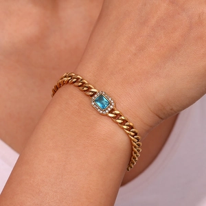 Detail of gold Cuban chain bracelet featuring a rectangular blue zircon centerpiece