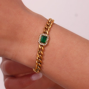 Detail of a gold Cuban link bracelet featuring a rectangular green zircon and pavé diamonds