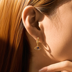 Nahaufnahme von 18K vergoldetem Evil Eye Ohrring mit blauem Stein an einem Model