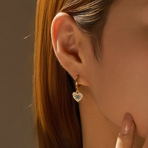 Detail eines 18K Gold-Herzohrrings mit bösem Auge Stein an einem Model für Mode