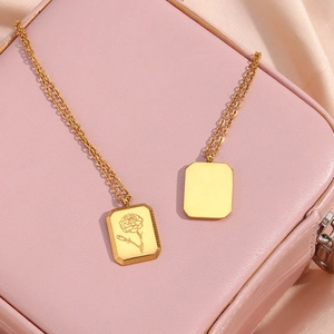 Macro shot of gold square pendant with floral engraving on elegant satin and leather background