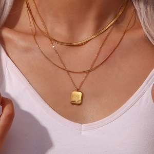 Three-piece layered gold necklace set with flat snake chain and rectangular flower pendant