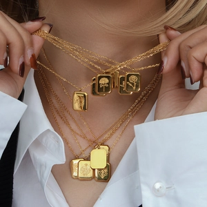 Detail of layered gold rectangular necklaces with intricate floral relief on model