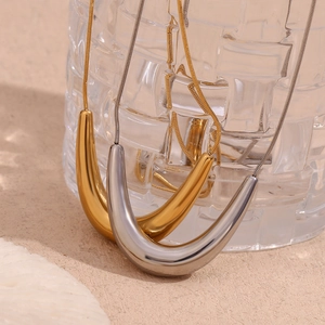Polished V-shaped gold and silver pendants on sleek snake chains in a warm-toned setting