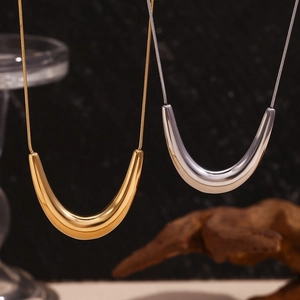 Detail of minimalist gold and silver U-shaped pendant necklaces on sleek snake chains