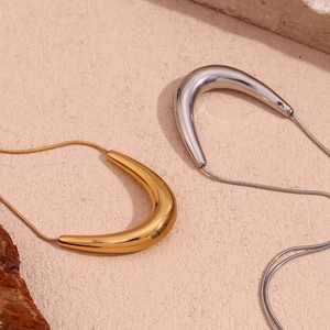 Detailed macro of minimalist gold and silver U-shaped pendants on fine snake chains