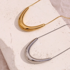 Detailed view of polished gold and silver V-shape pendants on snake chains
