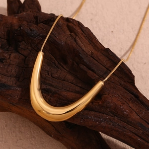 Detailed macro of a polished 18K gold-plated U-shaped pendant on a fine snake chain