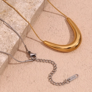 Macro detail of 18K gold-plated V-shaped pendant on sleek snake chain with lobster clasp