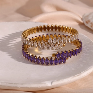 Detailed close-up of golden crossover bangle featuring marquise-cut white and purple zircons
