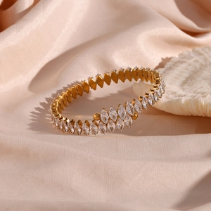 Macro detail of gold-plated bangle with marquise-cut zircons on champagne silk